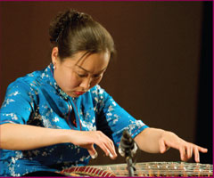 Лиу Фанг играет гуженг, китайской лютне цитры.